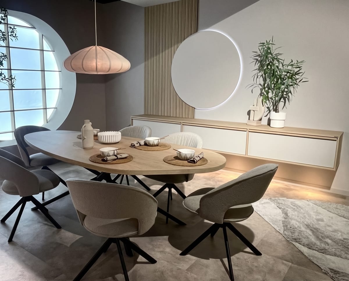 Mesa de madera y sillas grises junto a un aparador y espejo redondo